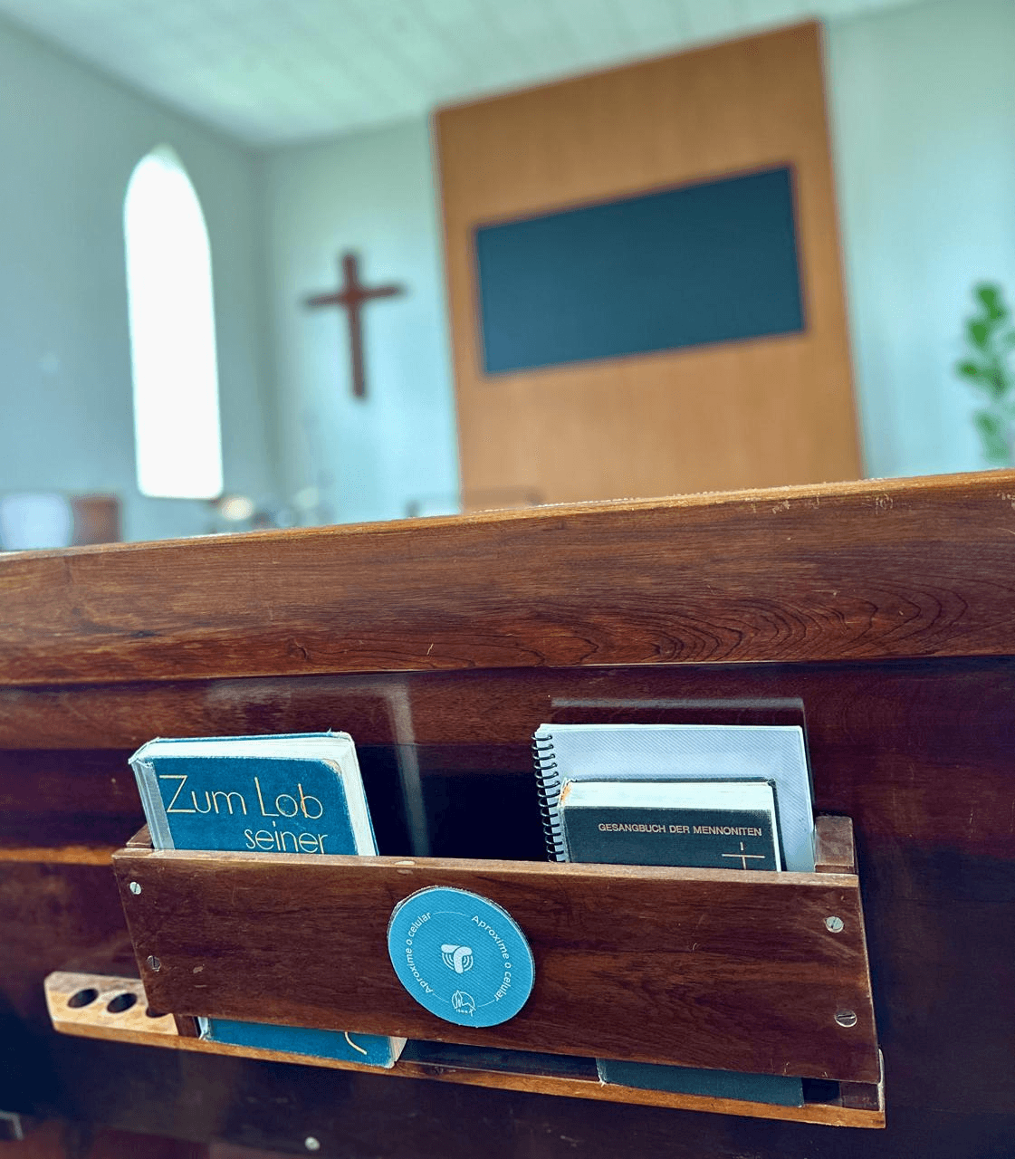 Tag TapWay fixada no porta-livros de um banco de igreja, com a frase 'Aproxime o celular'